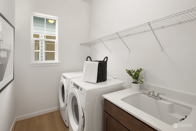 washroom with cabinets, light wood-type flooring, separate washer and dryer, and sink