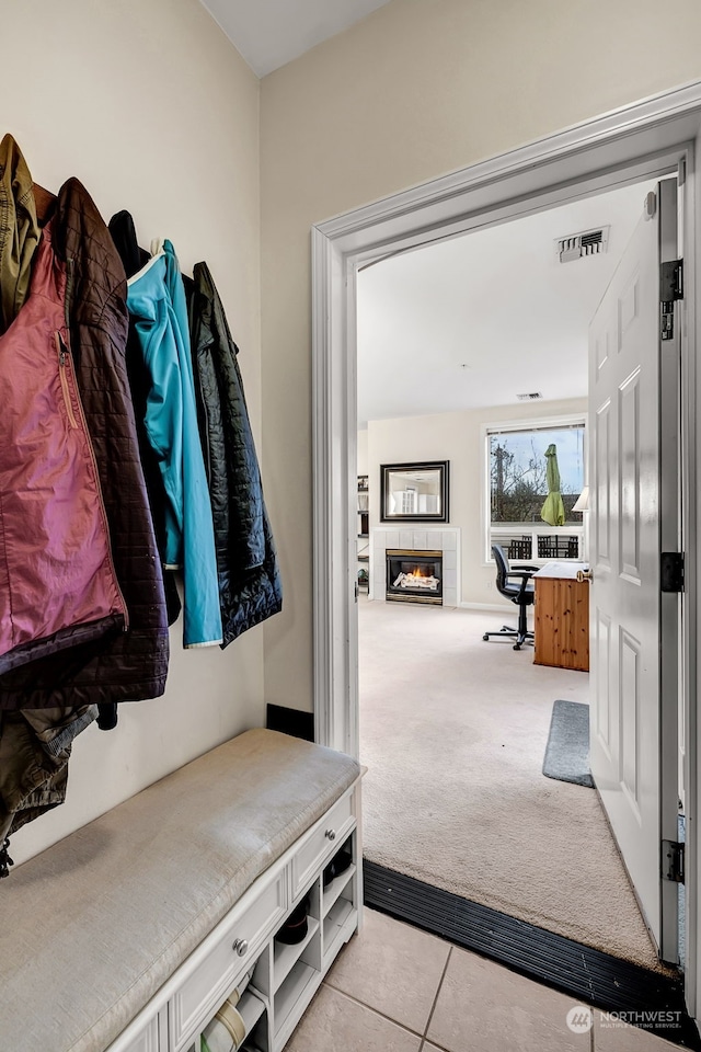 mudroom featuring light carpet and a tiled fireplace