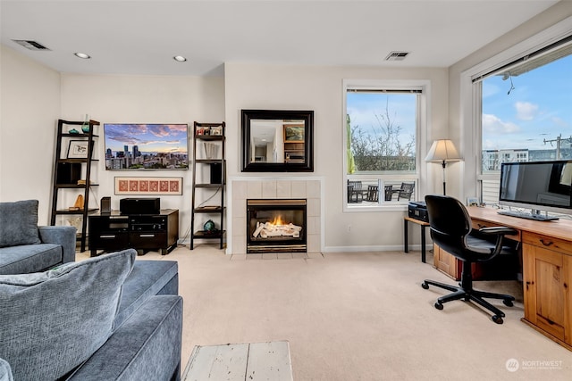 office space featuring a tile fireplace and light colored carpet