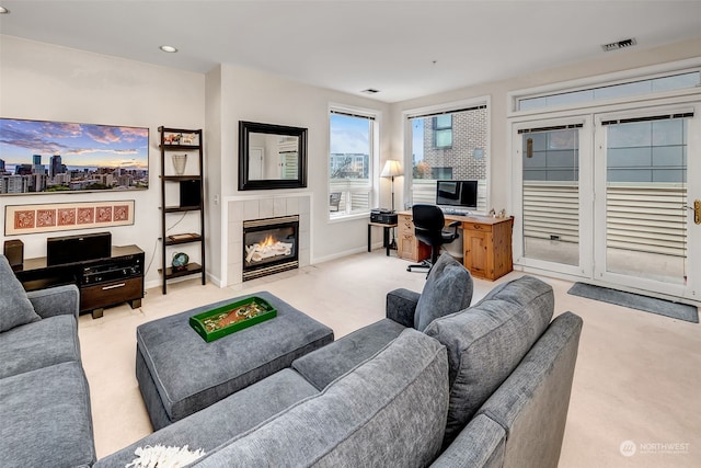 living room featuring a tiled fireplace, light carpet, and built in desk