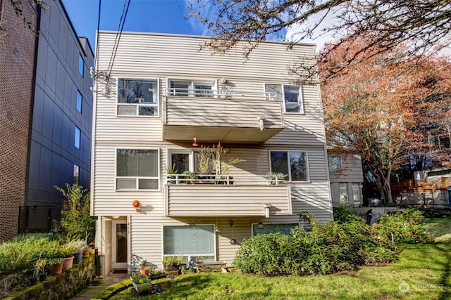 back of property with a yard and a balcony