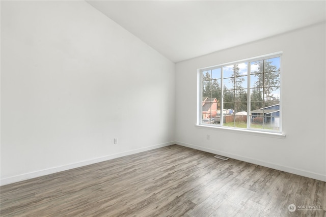 unfurnished room with wood-type flooring and vaulted ceiling