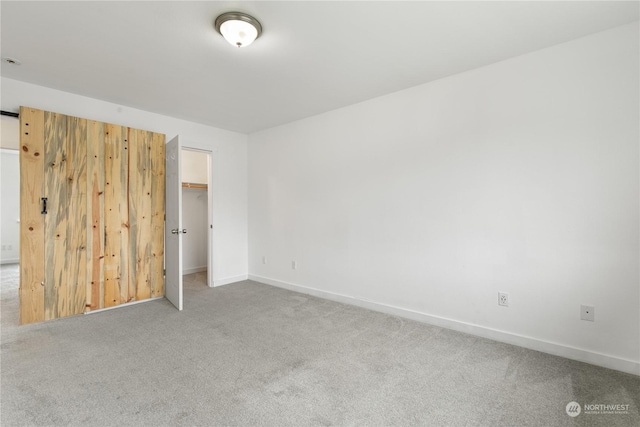 unfurnished bedroom with carpet flooring, a spacious closet, and a closet