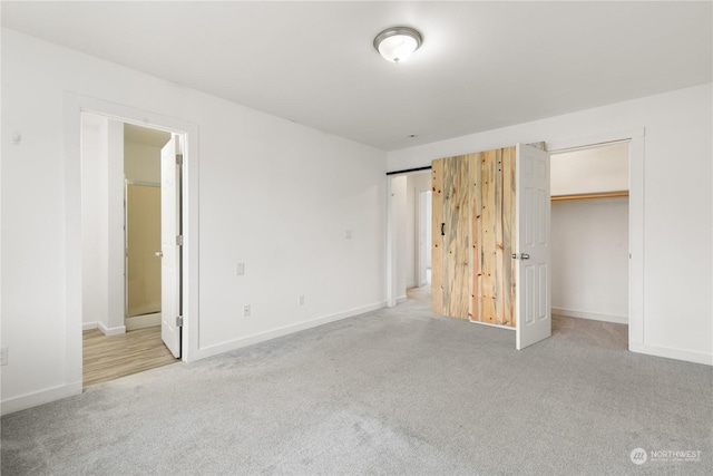 unfurnished bedroom featuring light colored carpet, ensuite bath, and a closet