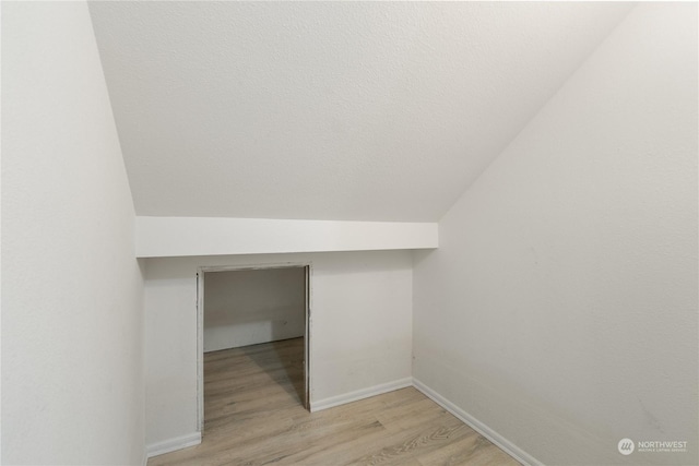 additional living space with light hardwood / wood-style floors and lofted ceiling