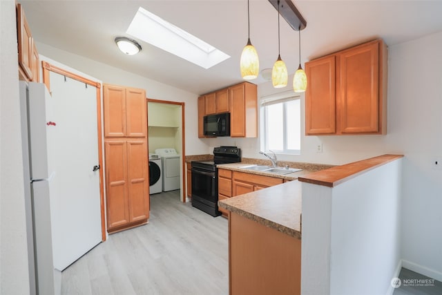 kitchen featuring vaulted ceiling with skylight, sink, black appliances, decorative light fixtures, and washing machine and dryer