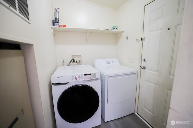 clothes washing area featuring ornamental molding, dark wood-type flooring, and washing machine and clothes dryer