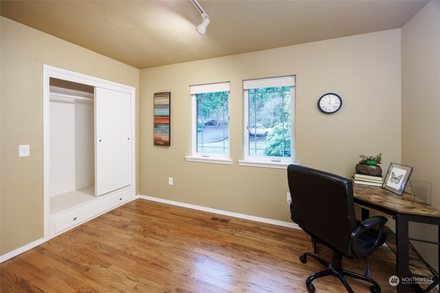 office area with hardwood / wood-style flooring and track lighting