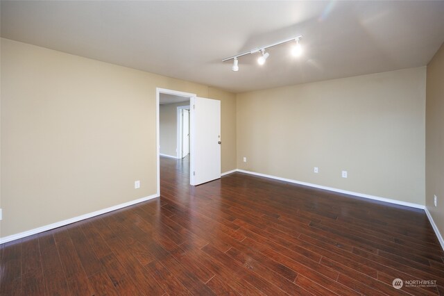 unfurnished room with dark hardwood / wood-style flooring and rail lighting