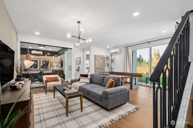 living room with light hardwood / wood-style floors, an AC wall unit, and an inviting chandelier