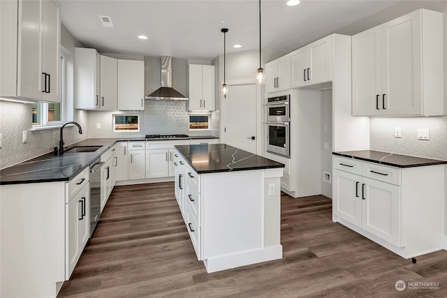 kitchen with dark hardwood / wood-style flooring, sink, wall chimney range hood, white cabinets, and a kitchen island