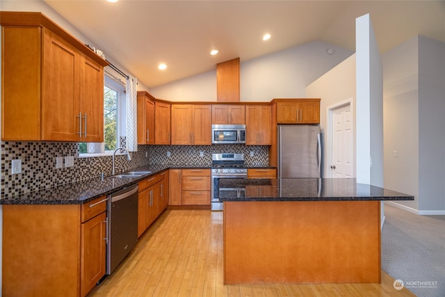 kitchen with sink, a kitchen island, vaulted ceiling, and appliances with stainless steel finishes