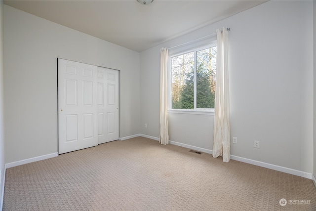 unfurnished bedroom featuring light colored carpet and a closet