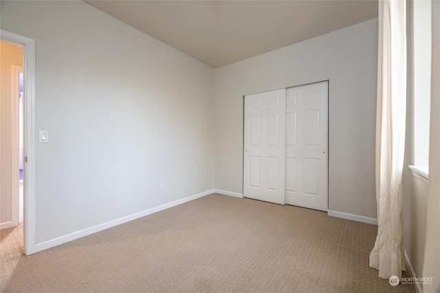 unfurnished bedroom with light carpet and a closet