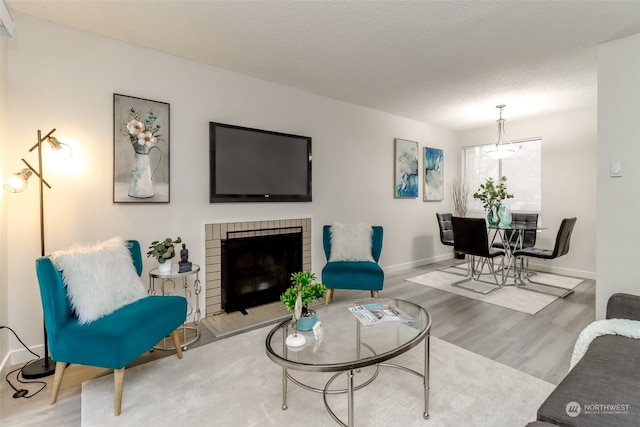 living room featuring a textured ceiling, light wood-type flooring, and a brick fireplace