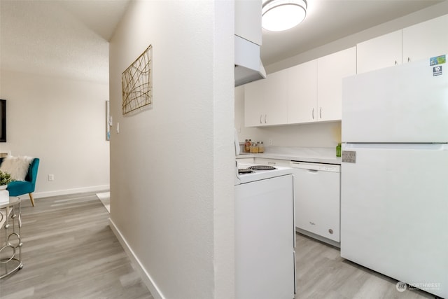 kitchen with a textured ceiling, light hardwood / wood-style flooring, white cabinets, and white appliances