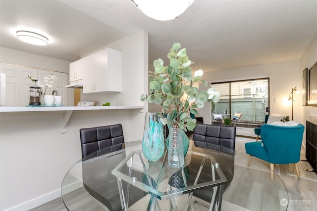 dining area featuring a textured ceiling and light hardwood / wood-style flooring