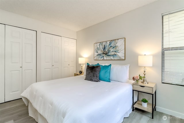 bedroom with multiple closets and light hardwood / wood-style flooring