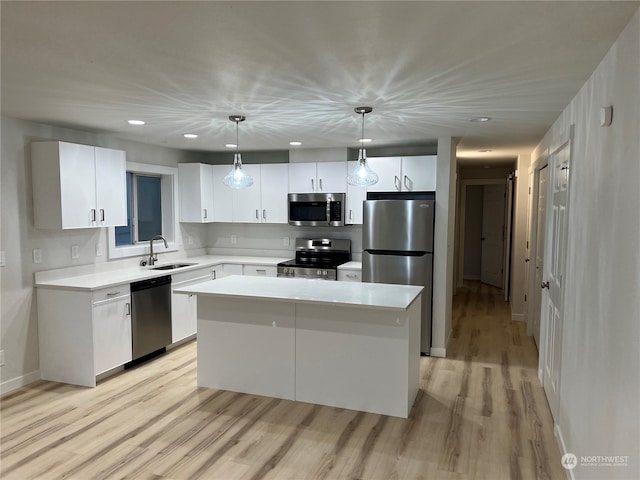 kitchen featuring white cabinets, a center island, hanging light fixtures, and appliances with stainless steel finishes