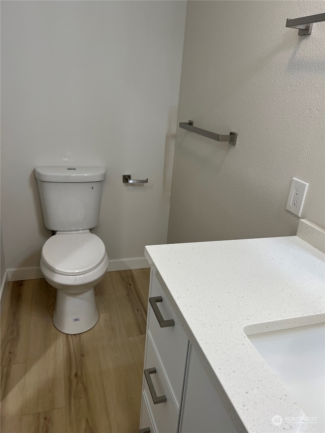 bathroom with wood-type flooring, vanity, and toilet