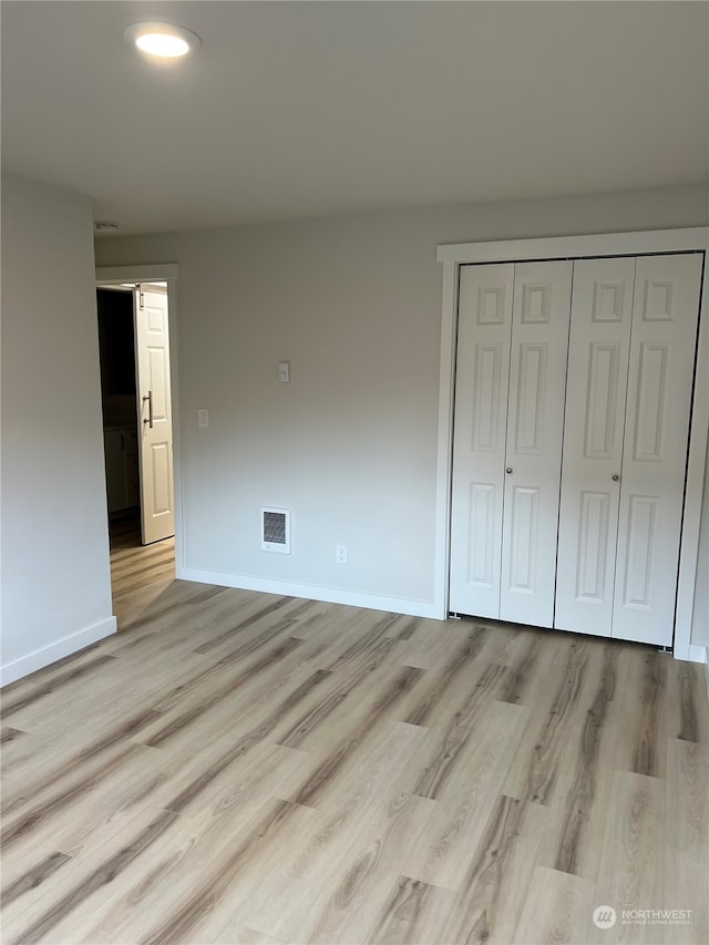 unfurnished bedroom featuring a closet and light hardwood / wood-style floors