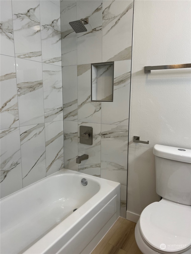 bathroom with hardwood / wood-style floors, tiled shower / bath combo, and toilet