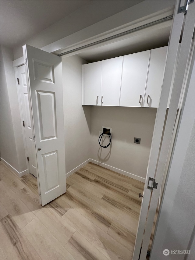 laundry area featuring hookup for an electric dryer, hookup for a washing machine, light hardwood / wood-style flooring, and cabinets