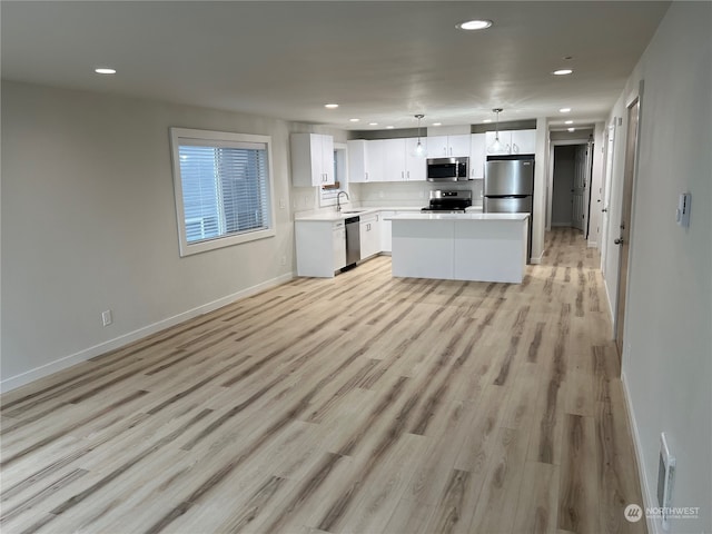 kitchen featuring sink, a center island, decorative light fixtures, white cabinets, and appliances with stainless steel finishes