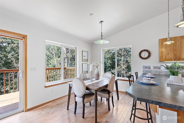 dining space with vaulted ceiling and light hardwood / wood-style flooring