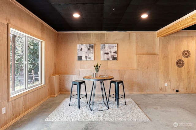 dining space featuring concrete flooring and wooden walls