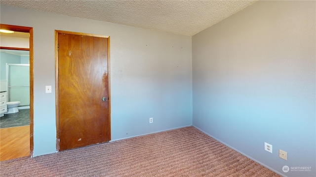 carpeted empty room featuring a textured ceiling