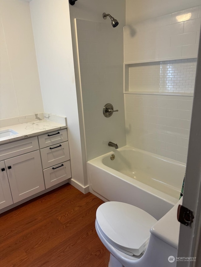 full bathroom with hardwood / wood-style flooring, tiled shower / bath combo, toilet, and vanity