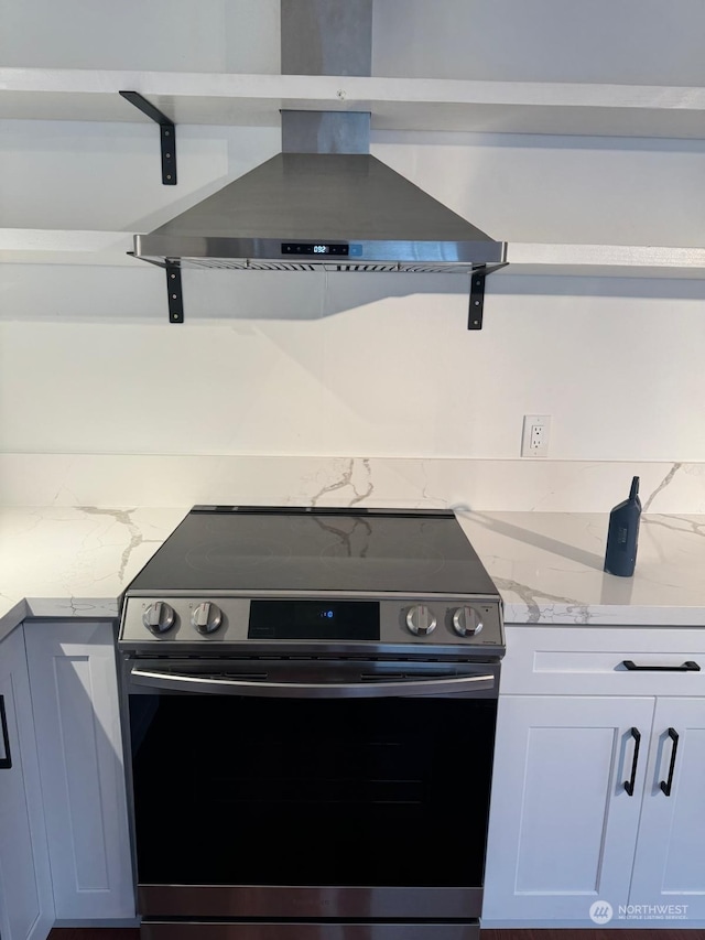 kitchen with stainless steel range, white cabinets, and range hood