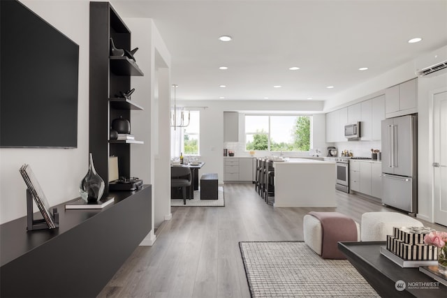 living room featuring sink, light hardwood / wood-style flooring, and a wall unit AC