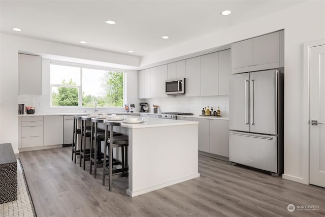 kitchen featuring a kitchen bar, appliances with stainless steel finishes, tasteful backsplash, light hardwood / wood-style flooring, and a center island