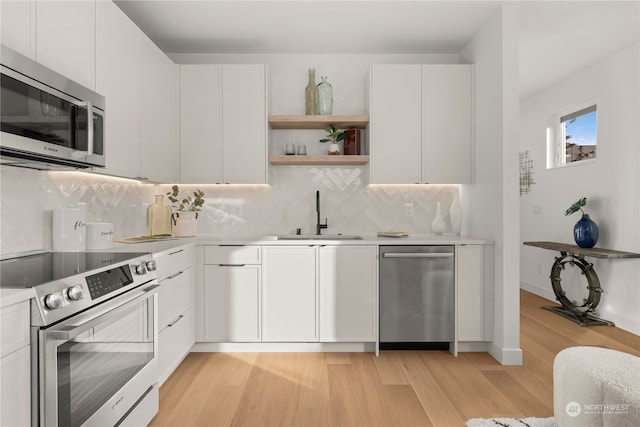 kitchen with light hardwood / wood-style flooring, stainless steel appliances, white cabinetry, and sink