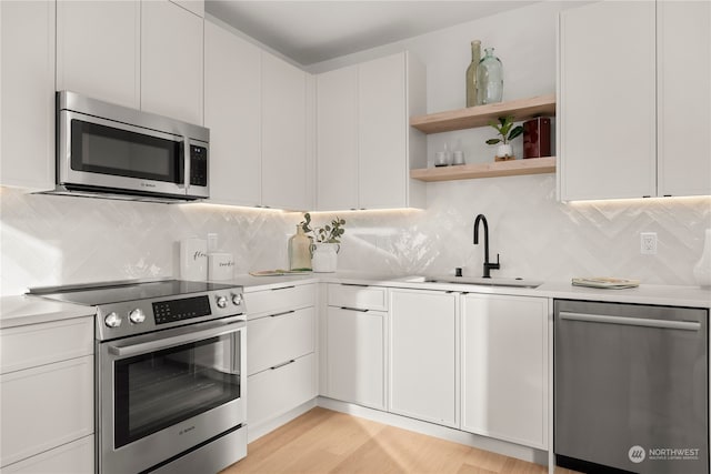 kitchen featuring white cabinets, light wood-type flooring, stainless steel appliances, and sink