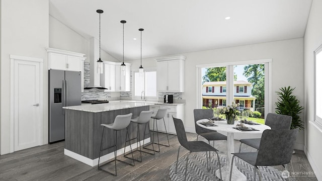 kitchen with a center island, stainless steel fridge with ice dispenser, lofted ceiling, decorative backsplash, and white cabinets