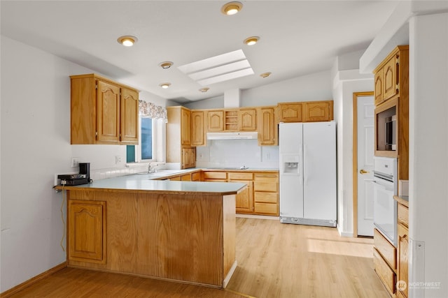1100 S Rosewood Dr Unit 405, Ellensburg, WA 98926 - kitchen with white appliances, a peninsula, under cabinet range hood, a skylight, and vaulted ceiling