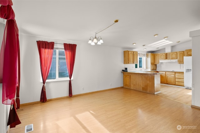 kitchen with kitchen peninsula, light wood-type flooring, decorative light fixtures, and white fridge with ice dispenser