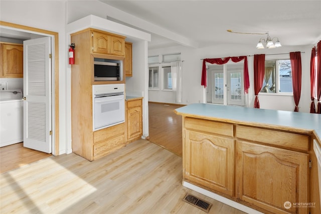 1100 S Rosewood Dr Unit 405, Ellensburg, WA 98926 - kitchen with oven, stainless steel microwave, washer / dryer, light wood-style floors, and a chandelier
