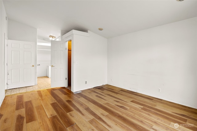 unfurnished bedroom with light wood-type flooring and vaulted ceiling