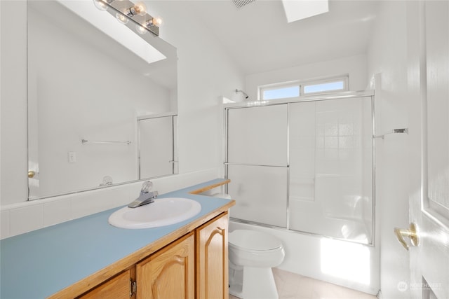 full bathroom featuring toilet, combined bath / shower with glass door, lofted ceiling with skylight, and vanity