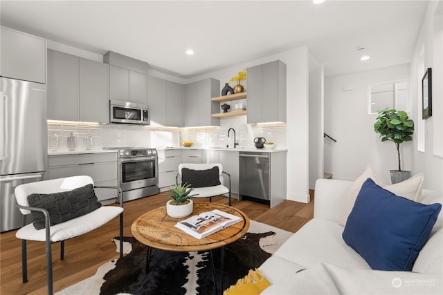 kitchen with decorative backsplash, appliances with stainless steel finishes, gray cabinets, and light hardwood / wood-style flooring