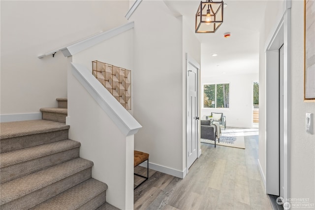 stairs with a notable chandelier and wood-type flooring