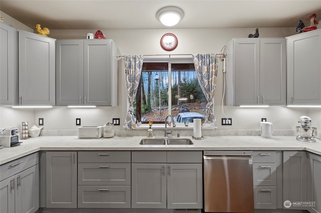 kitchen with light stone counters, sink, gray cabinets, and stainless steel dishwasher