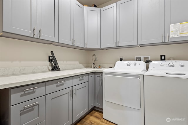 clothes washing area featuring cabinets, separate washer and dryer, sink, and light hardwood / wood-style floors