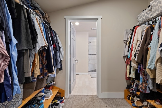 spacious closet with vaulted ceiling and light colored carpet