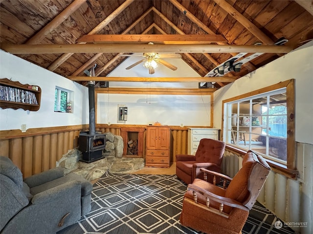 living room with a wood stove, ceiling fan, vaulted ceiling with beams, wood walls, and wood ceiling