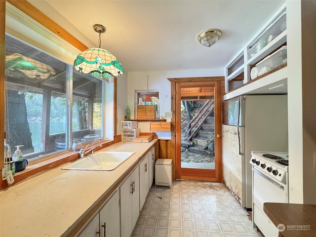 kitchen featuring pendant lighting, white range, white cabinetry, and sink